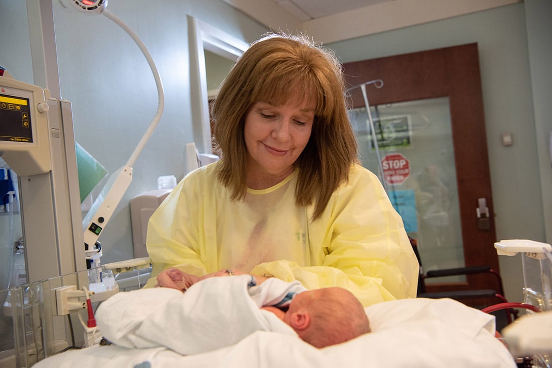 A labor and delivery nurse smiles as she cares for a newborn infant.