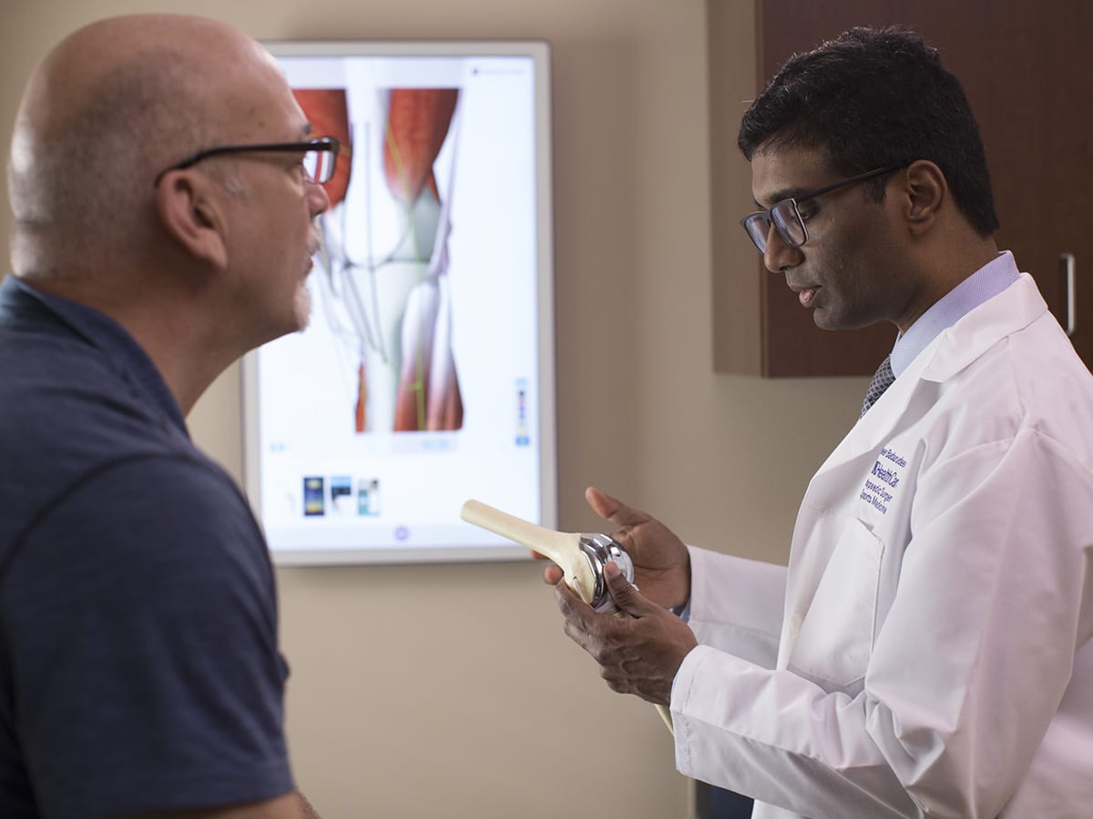 Doctor Badarudeen explains knee replacement surgery to a patient.