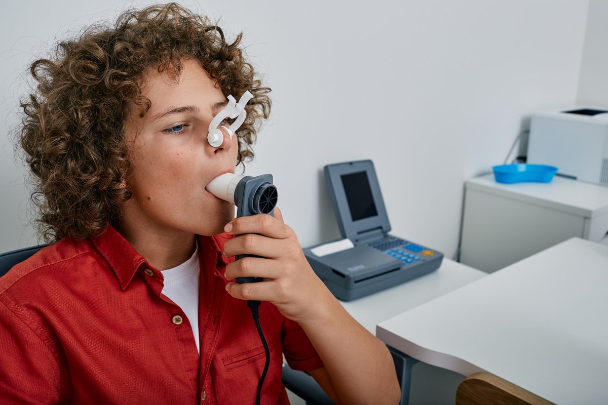 Young man using a device to measure pulmonary function.